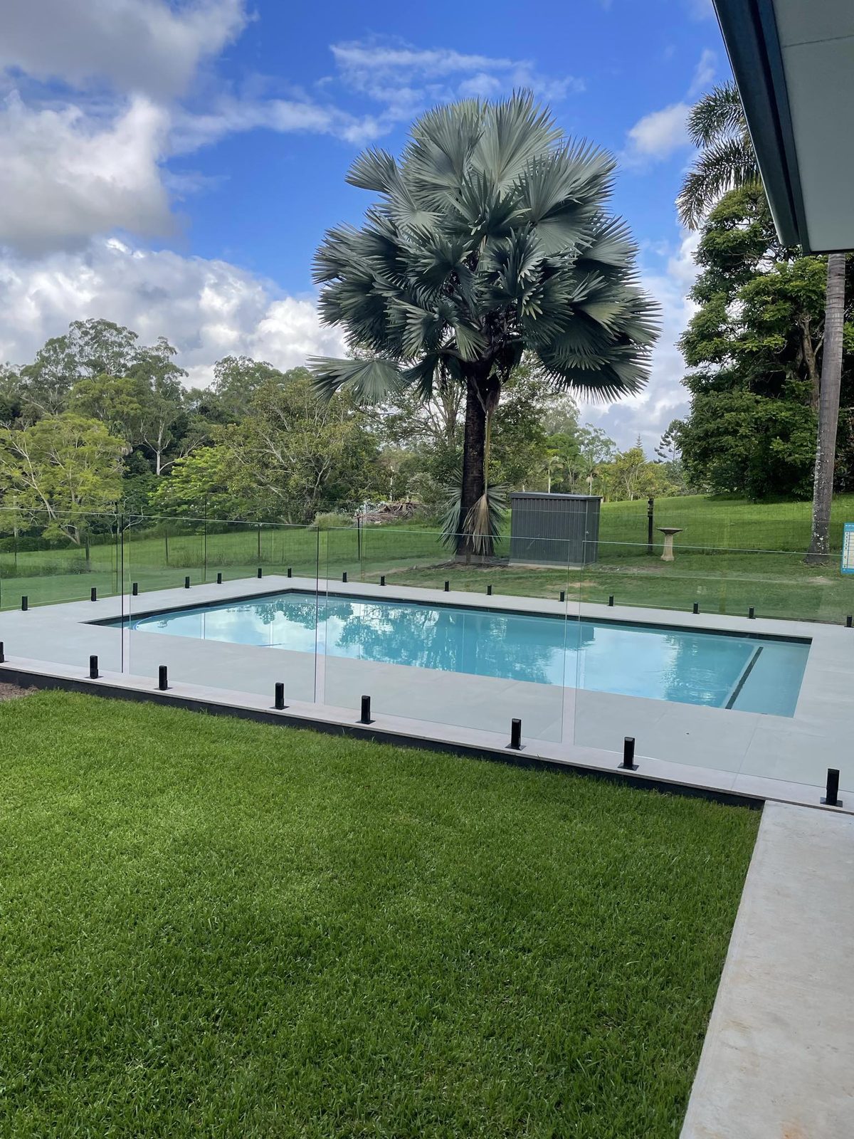 Frameless glass pool fence with black mini posts around an in-ground pool on a Sunshine Coast acreage